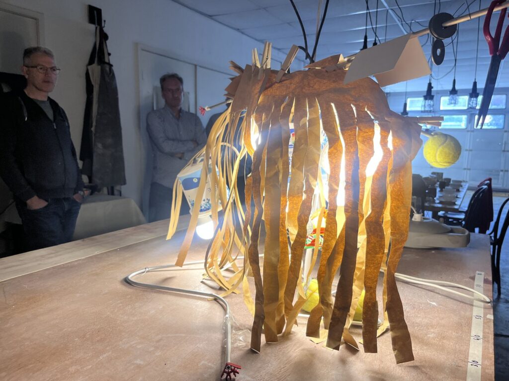 Een zelfgebouwde lamp van papier brandt in het atelier